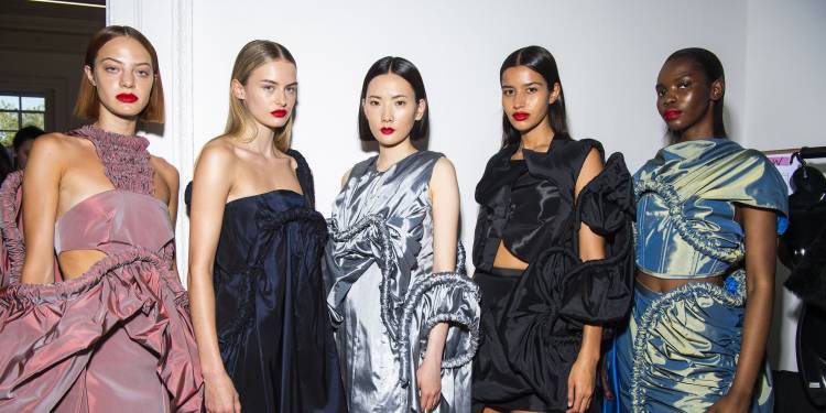 Five models wearing intricate fashion designs
